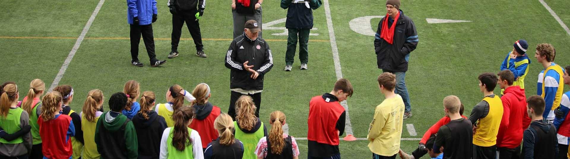 Photo of dozens of players huddled around a coach.